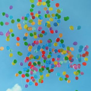 Flerfärgade balonger som svävar fritt i den klar blåa himmeln