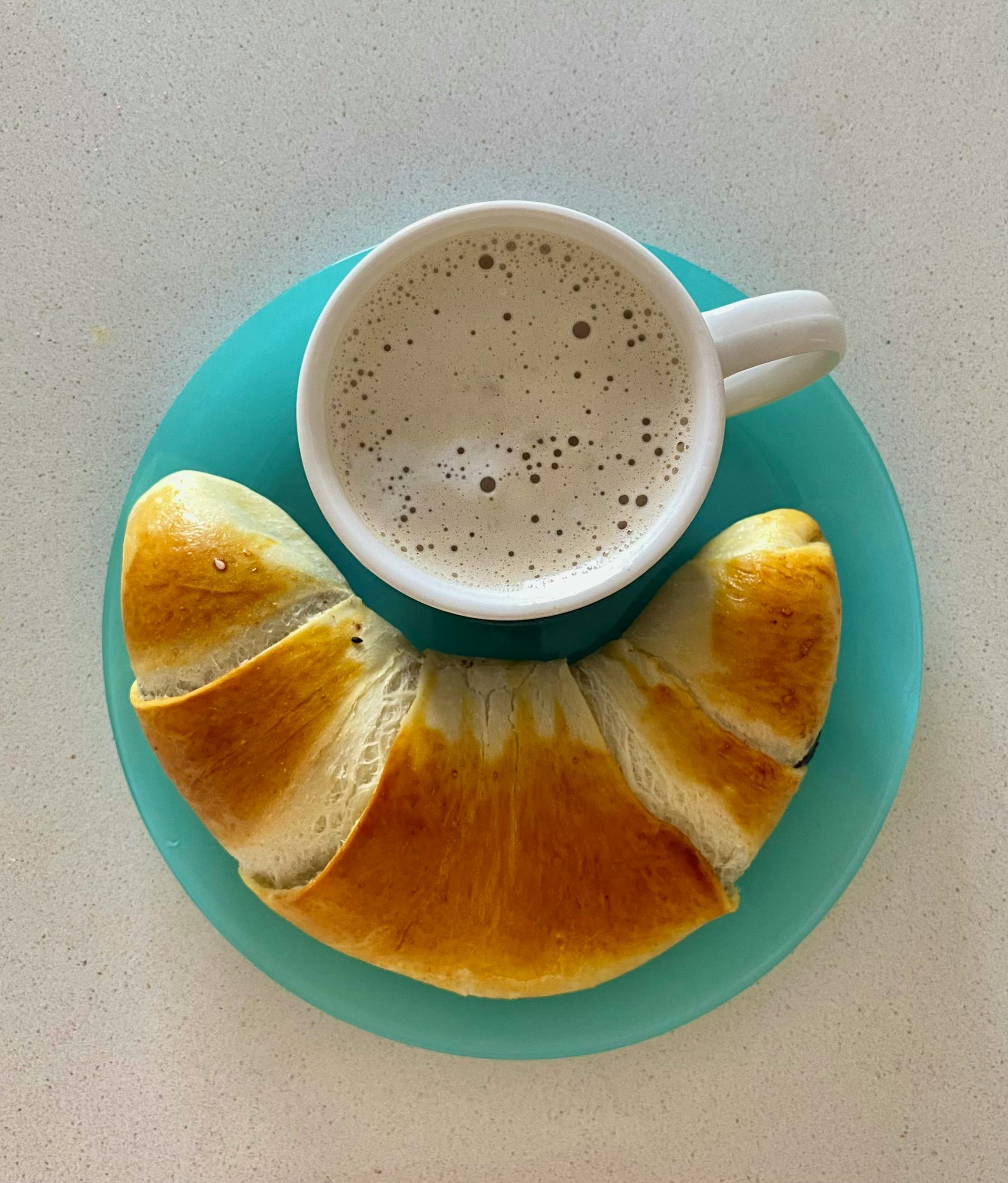 En kaffe och en bulle på en tallrik.