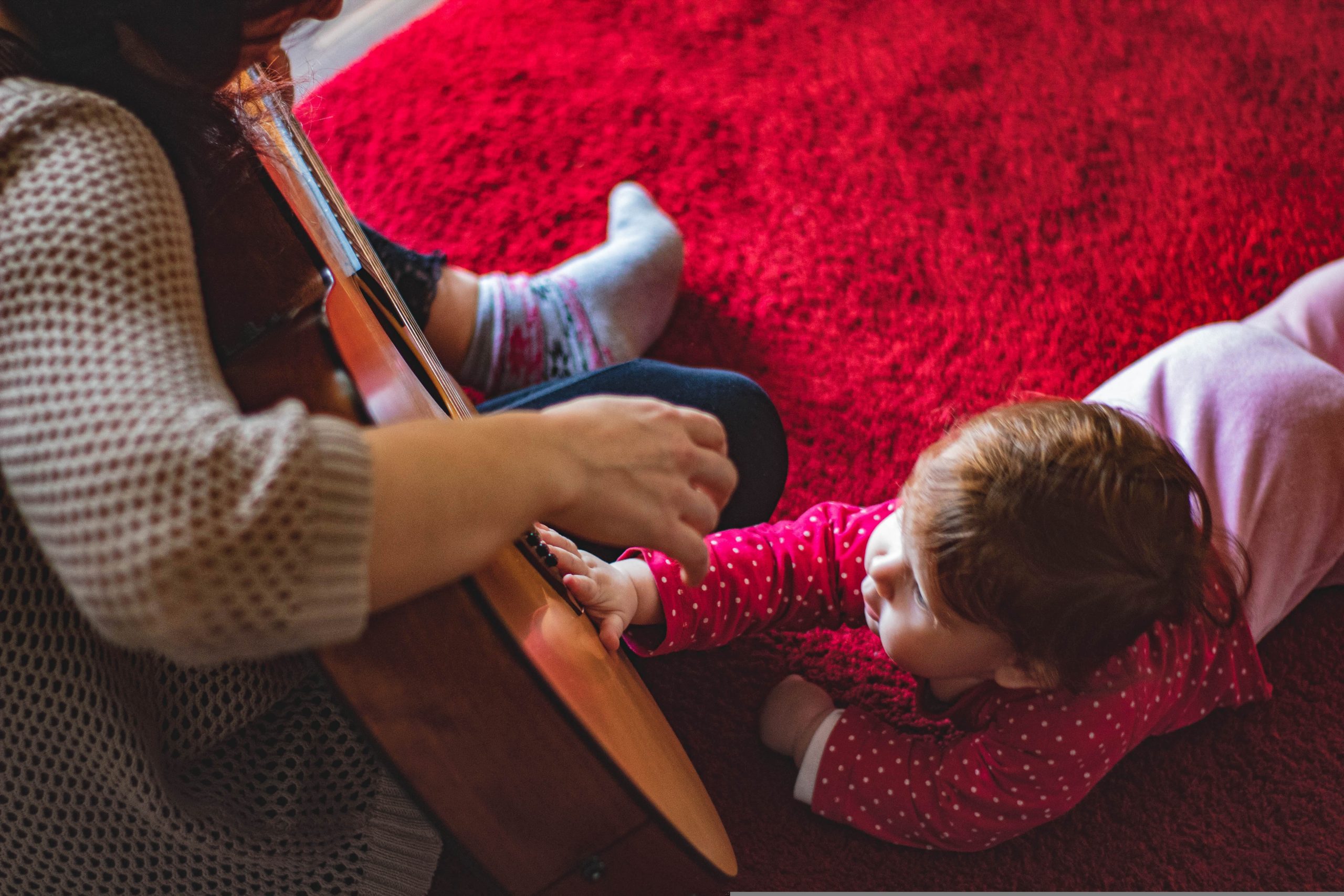 vuxen spelar gitarr sjunger för småbarn spädbarn bebis