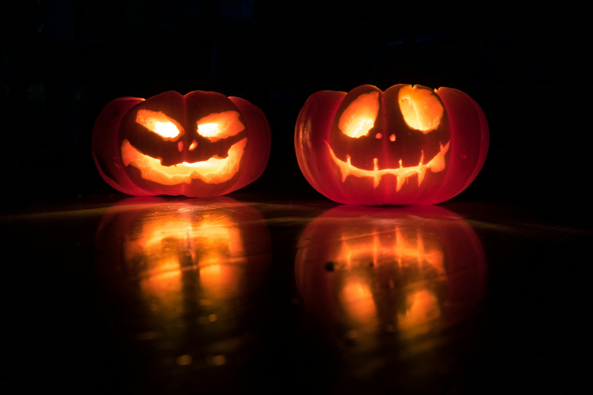 Två lysande halloweenpumpor i ett mörkt rum