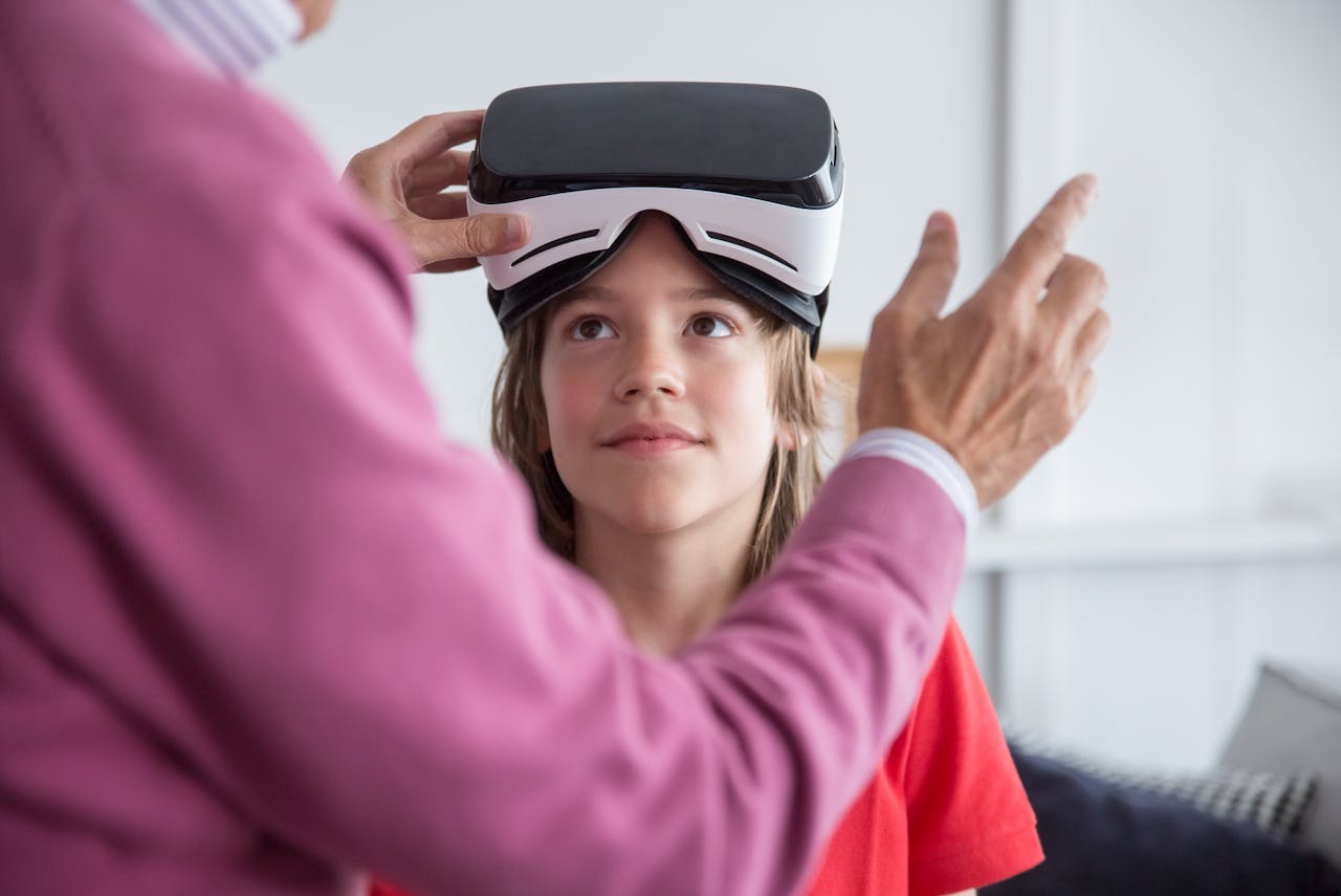 En bild på en vuxen som hjälper en tjej i cirka tio års ålder med ett VR headstet.