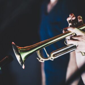 En trumpet som ett par händer spelar på i en mörk bakgrund.
