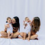 Två kvinnor med varsitt spädbarn mot vit bakgrund