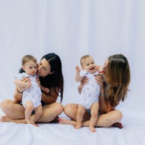 Två kvinnor med varsitt spädbarn mot vit bakgrund