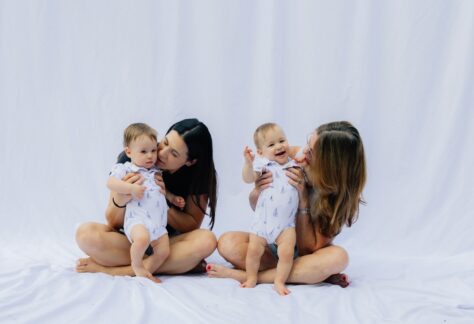 Två kvinnor med varsitt spädbarn mot vit bakgrund