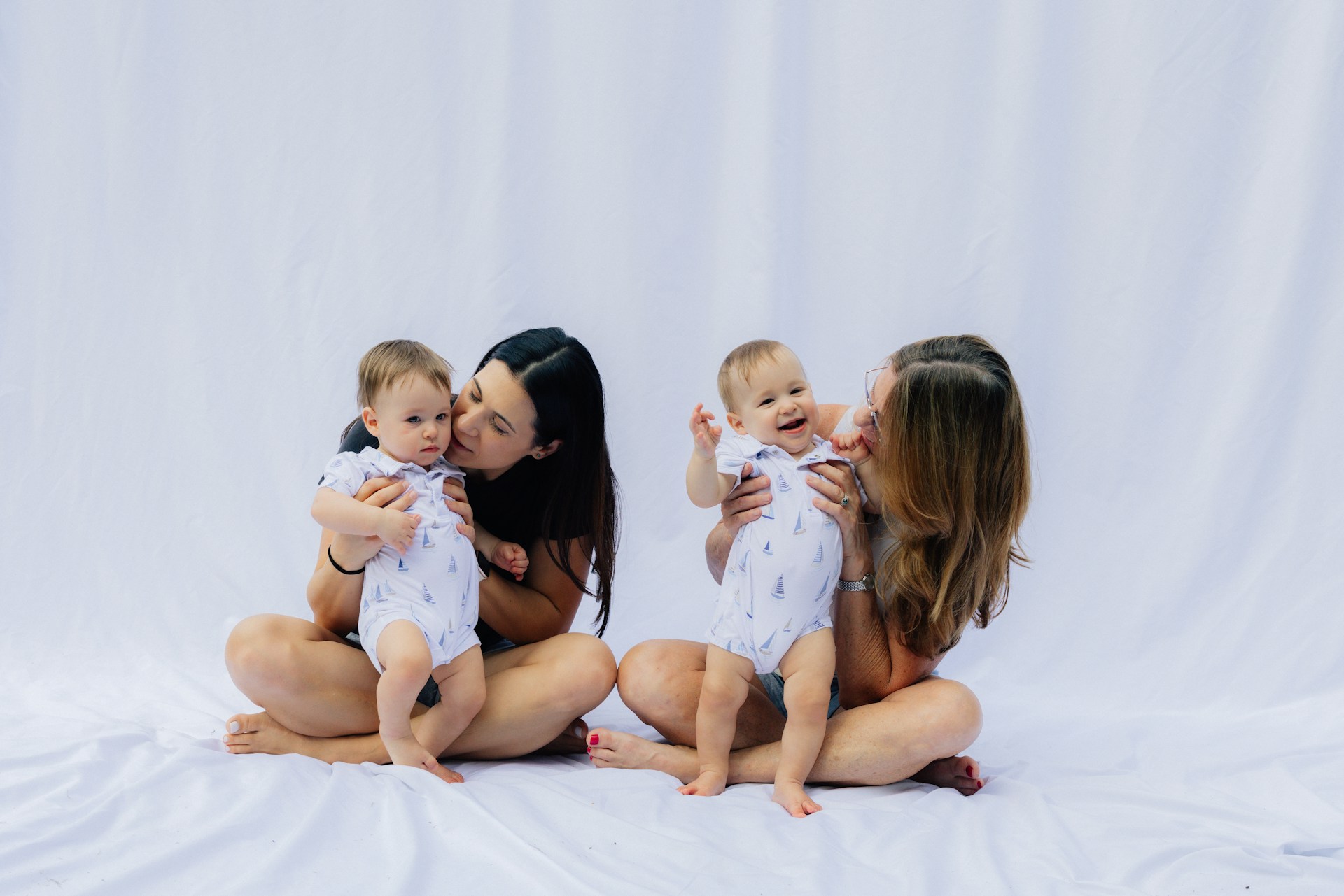 Två kvinnor med varsitt spädbarn mot vit bakgrund
