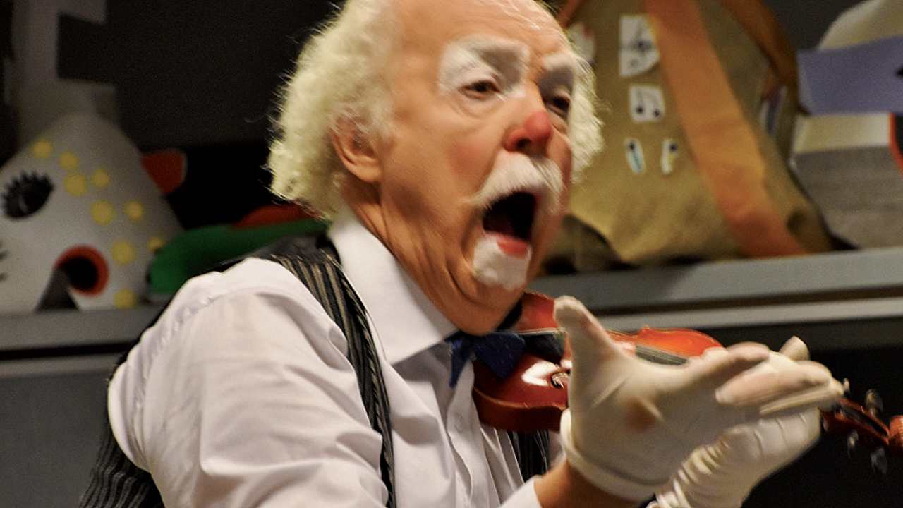 Clownen Raimondo spelar på en pytteliten fiol