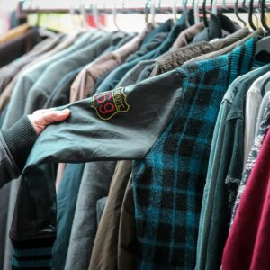 Hängande kläder på galgar (second hand) och en person som känner på en jacka.