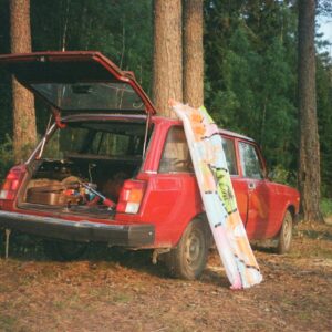 Bild på en röd bil som har öppen baklucka i en skog.