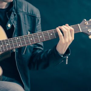 Foto på person som spelar akustisk gitarr.