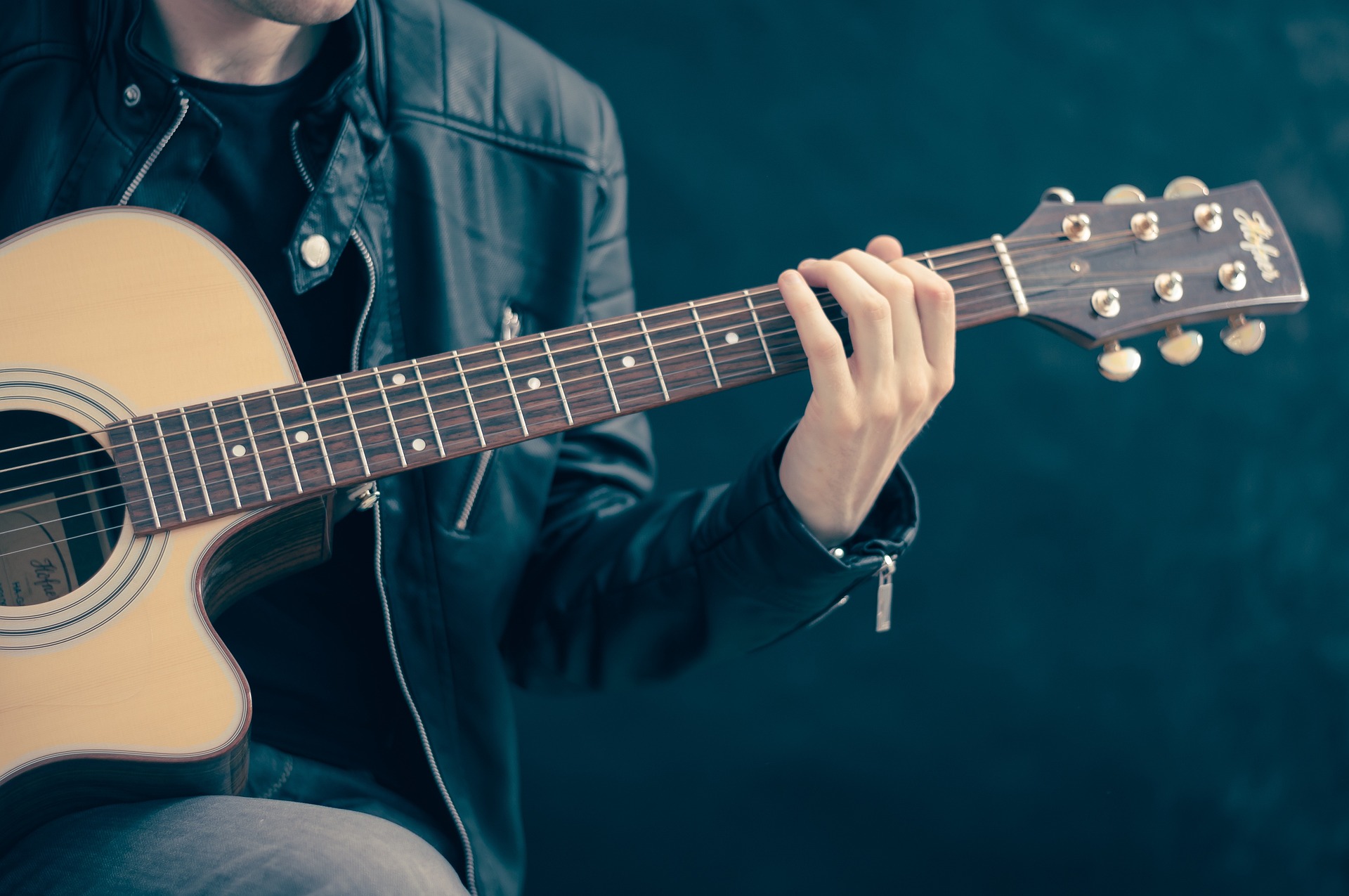 Foto på person som spelar akustisk gitarr.