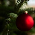 Bild på en röd julkula som hänger i en julgran.