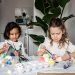 Två barn som sitter vid ett bord och påskpysslar.