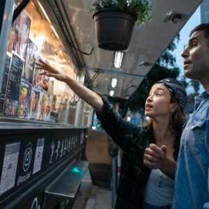 Två människor står och väljer från en meny på en food truck