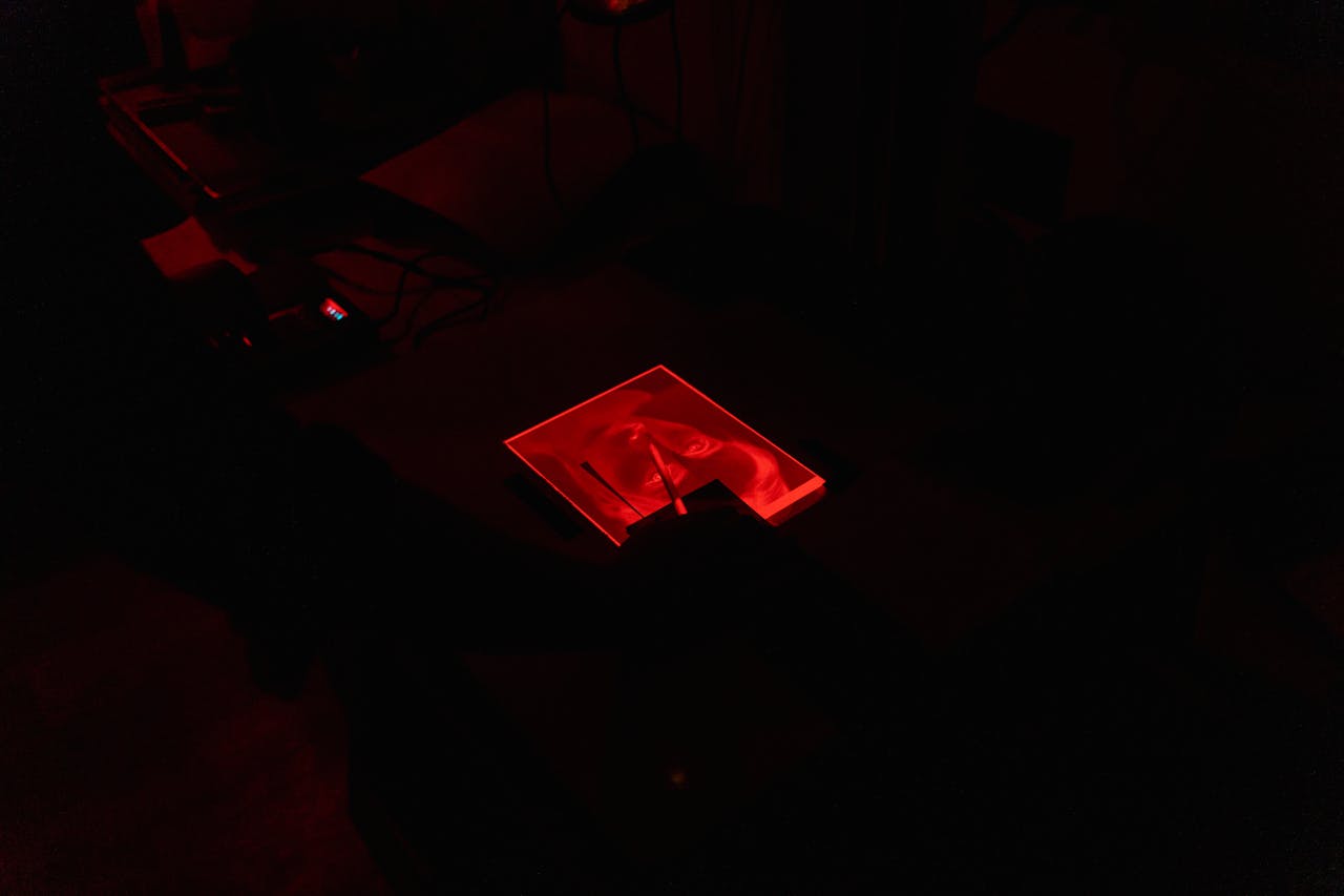 Bild på analog fotografering i ett mörkt rum med röd belysning.