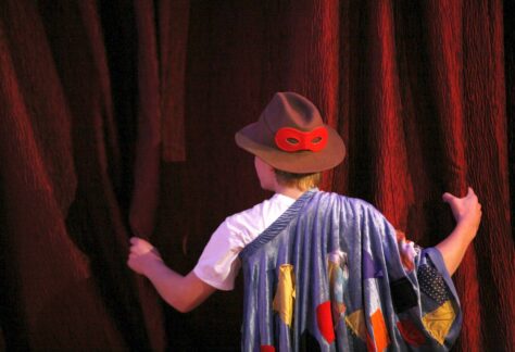 Yngling bakom teaterdraperi.