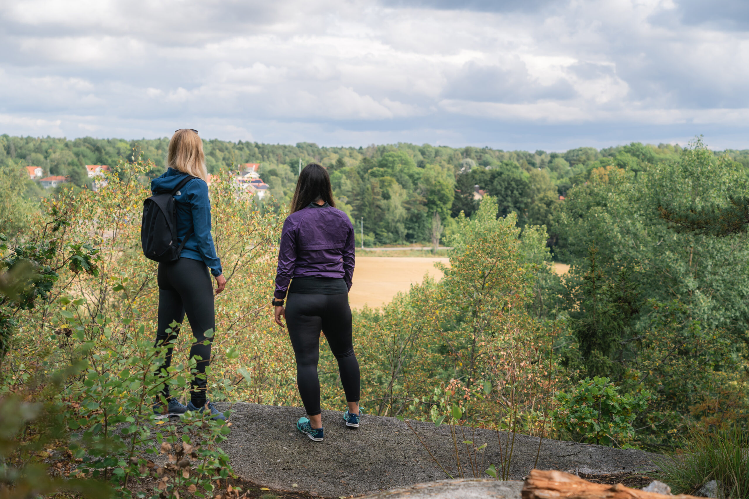 Bild på två personer som står ute i naturen.