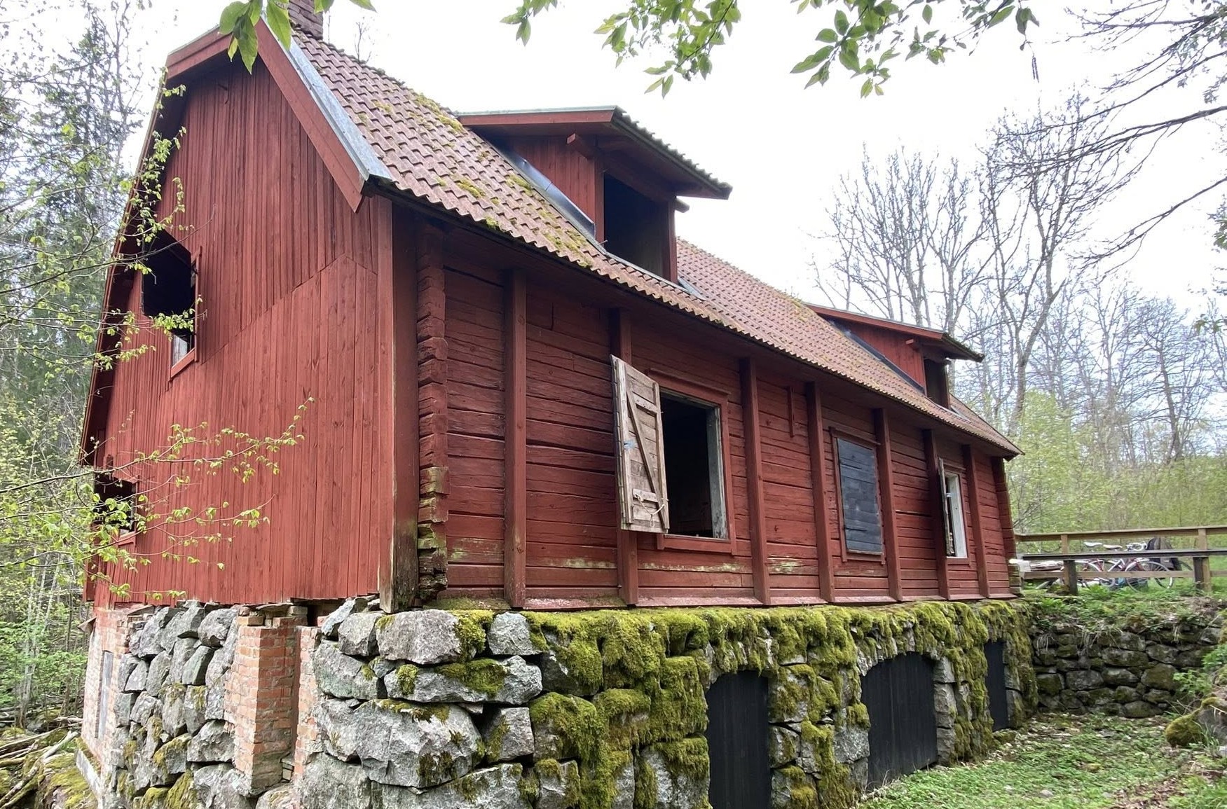 En gammal faluröd kvarnbyggnad med omgivande natur, Kvarnbo kvarn.