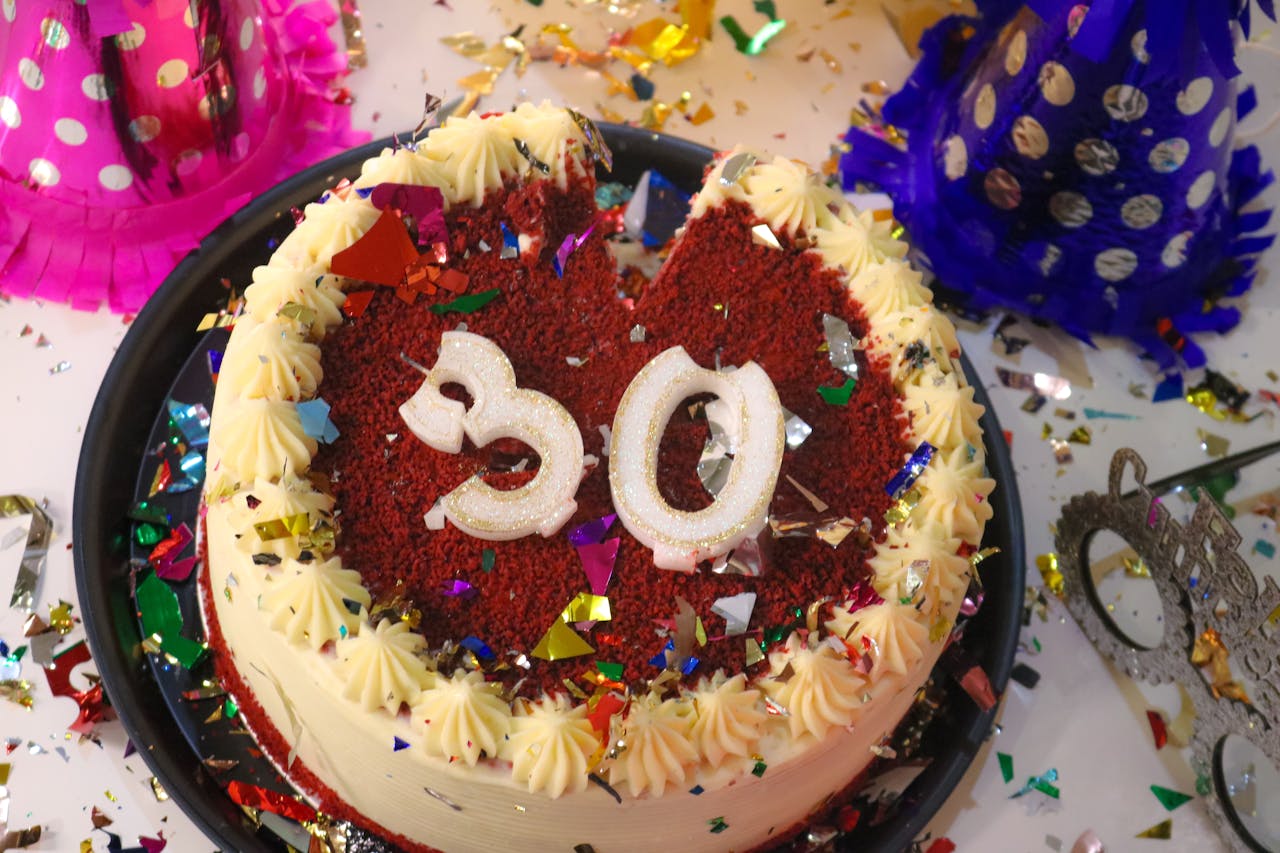 Bild på en tårta som det står "30" på. Tårtan står på ett bord med dekorationer och partyhattar.