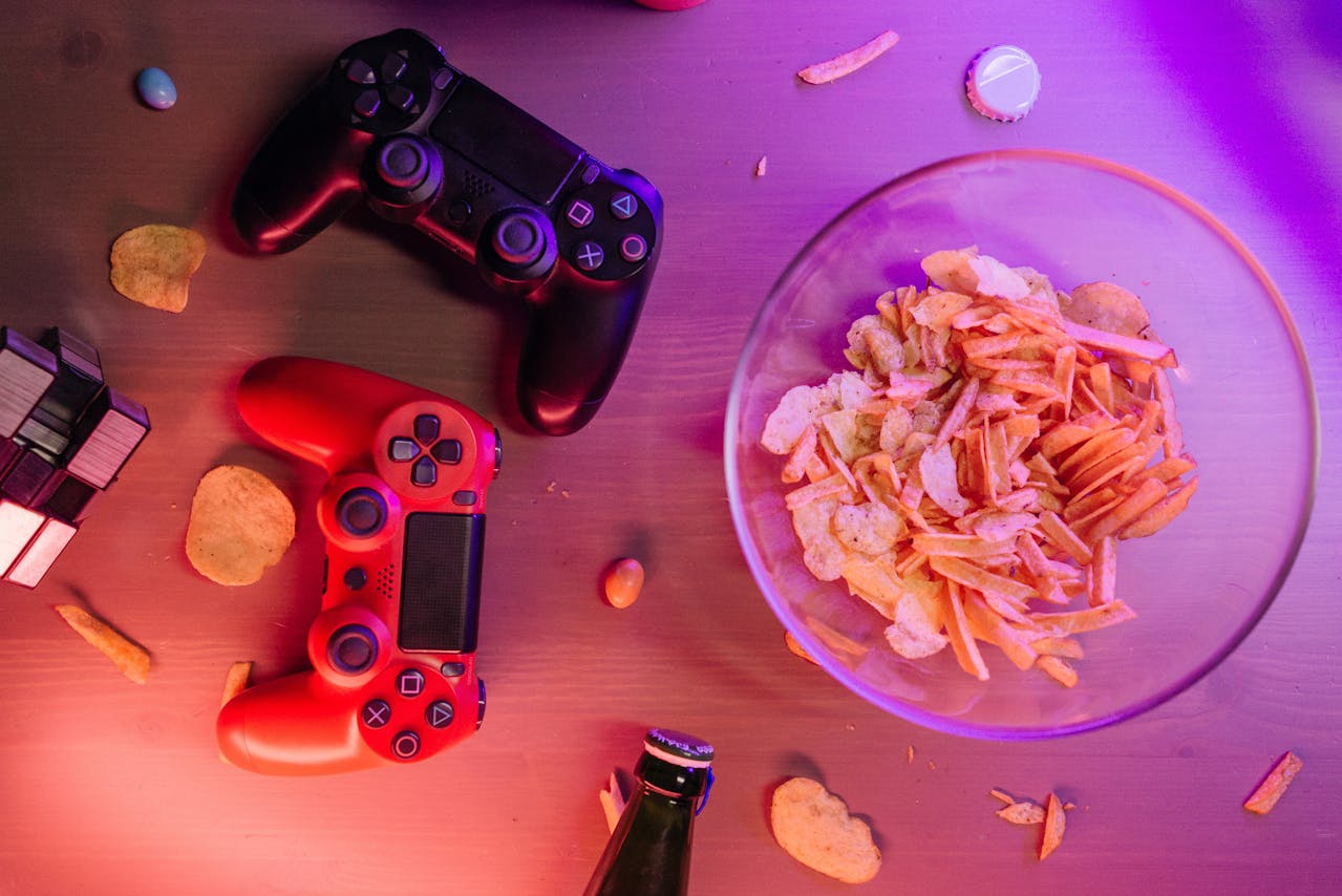 Bild på två playstation-kontroller på ett bord och en skål chips bredvid.