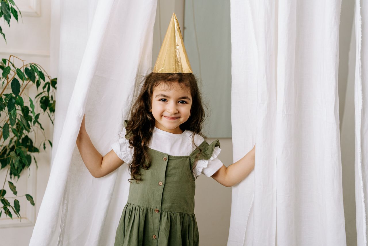En liten festklädd flicka med guldfärgad partyhatt
