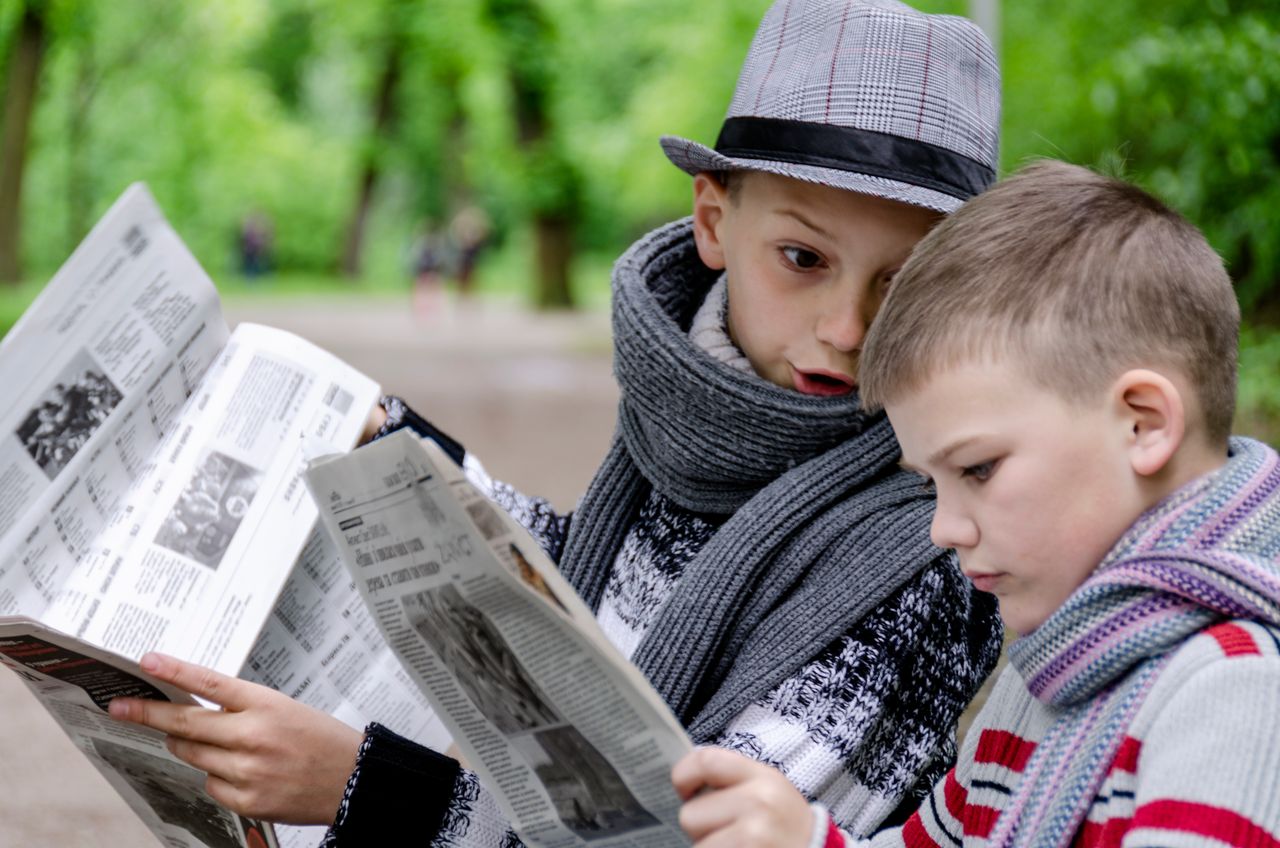 Två unga pojkar läser varsin tidning
