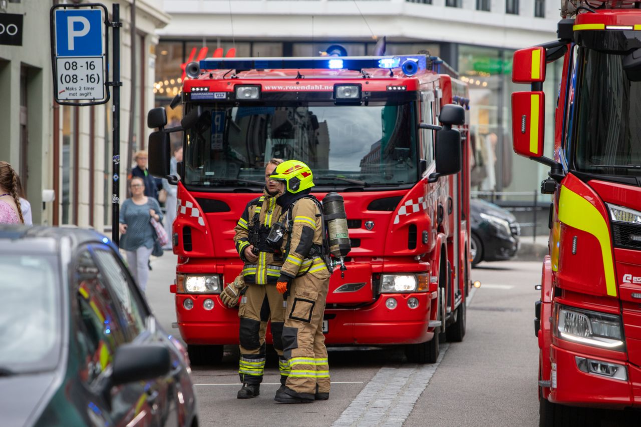 Brandmän i utrustning står framför brandbilar på en stadsgata, redo för räddningsinsats.