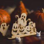 En festlig Halloween-inspirerad utsmyckning med träspöken och pumpor.