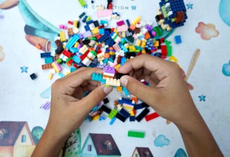 Bild på två händer som bygger med massor av lego.