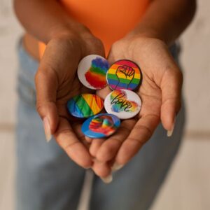 Bild på två händer som håller i olika Pride-pins.