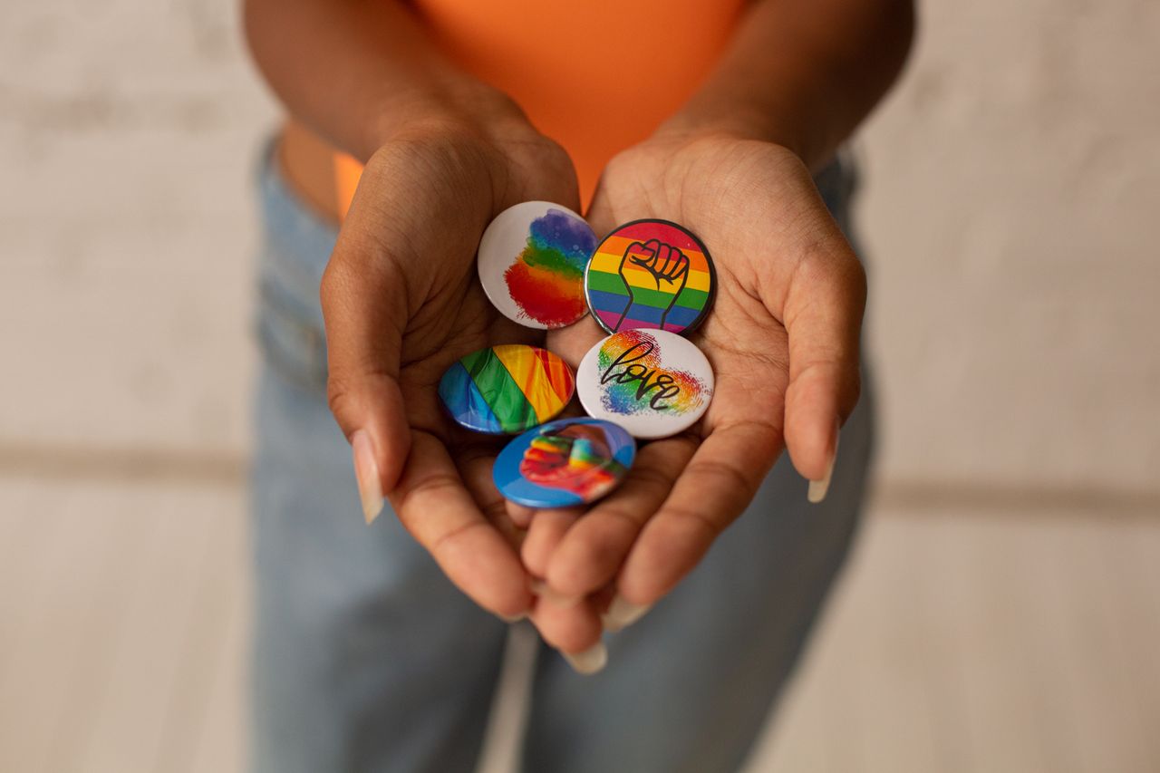 Bild på två händer som håller i olika Pride-pins.