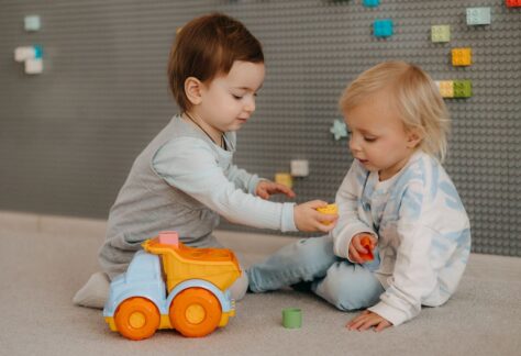 två små barn som ger varandra leksaker.