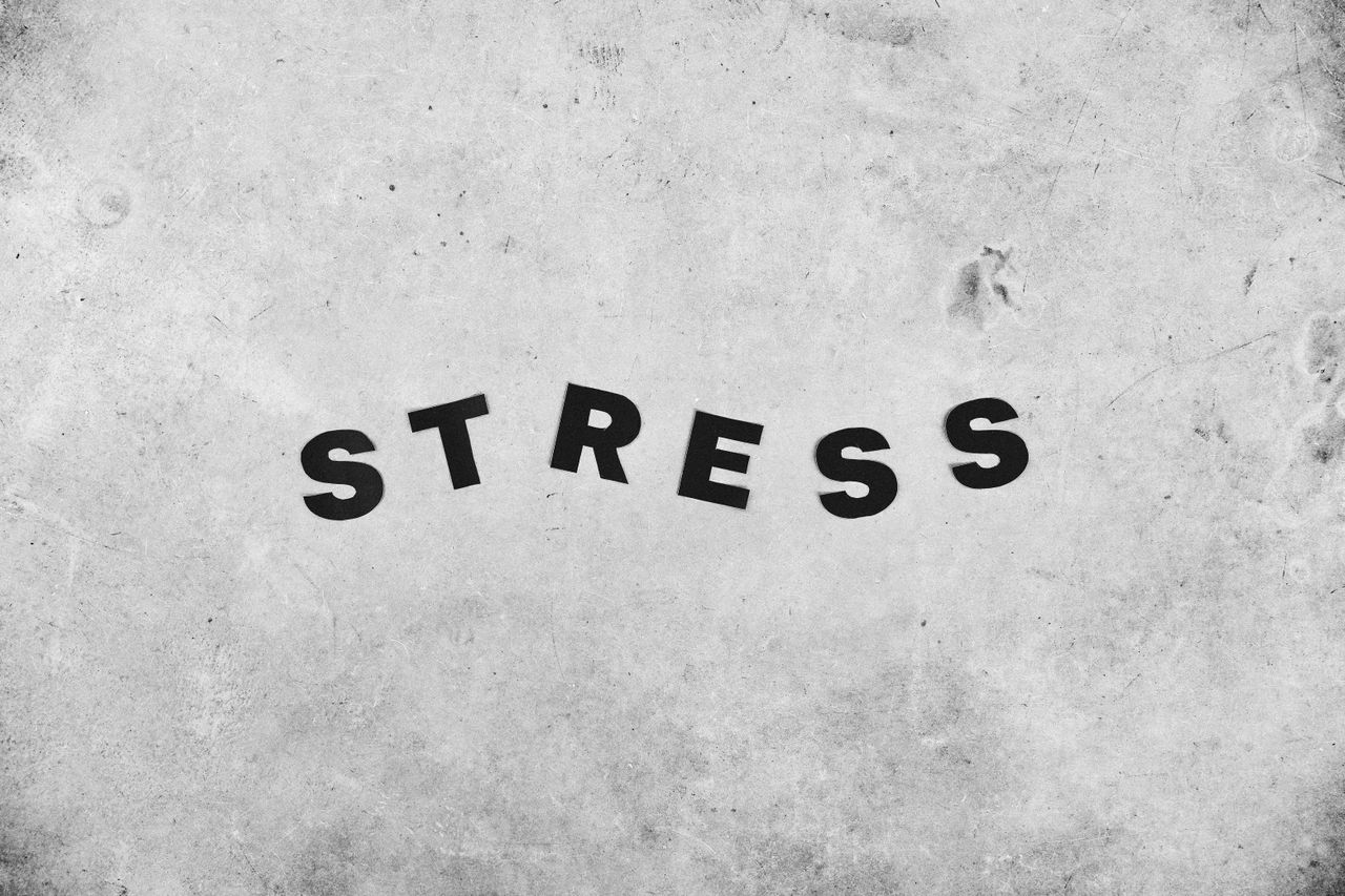 En grå bakgrund med ordet "stress" i svart på.